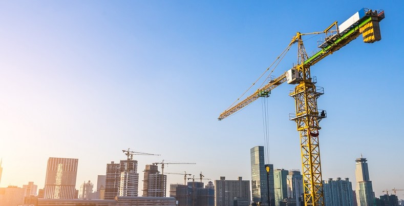 A construction site with a large tower crane against a city skyline
